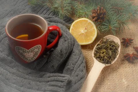 Red cup of tea with pattern in heart shape wrapped up in wool scarf. 스톡 사진