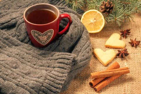 Red cup of tea with pattern in heart shape wrapped up in wool scarf. Stock Photos