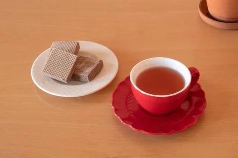 Red cup of tea with wafer biscuits on a wooden table. Tea break and sweet s.. Stock Photos