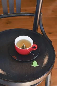 A red cup with tea is wrapped in a warm Christmas sweater, a tea bag label Stock Photos