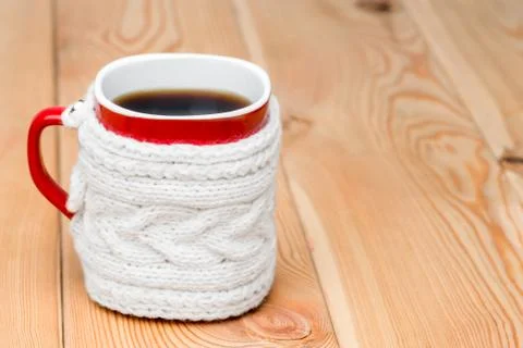 Red cup in white knitted sweater with hot tea on wooden boards Stock Photos