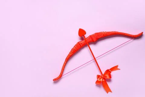 Red cupid's bow on lilac background. Valentine's Day celebration Stock Photos