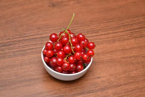 Red currant in the plate on the table. Stock Photos