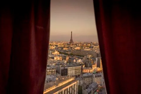 Red curtained window view of cityscape with distant Eiffel Tower, Paris, Fran Foto stock