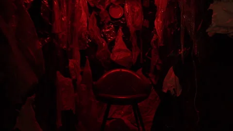Red dark room made of trash with a chair in the center. Stock Footage 289401157