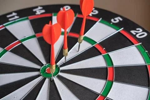 Red dart arrows hitting in the target center of dartboard. Success hitting .. Stock Photos