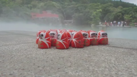 Red Daruma dolls rest on stone platform at Katsuoji Temple in Osaka, surrounded Stock Footage 344279275