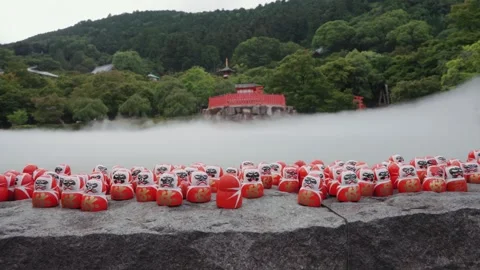 Red Daruma dolls on stone platform at Katsuoji Temple in Osaka, surrounded by Stock Footage 345186194