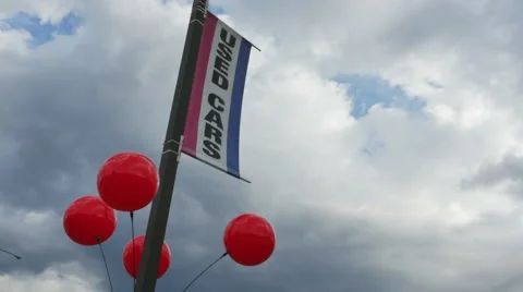 Red decorative balls bob in the wind on used car pole against cloudy sky Stock Footage 57535045