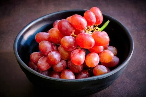 Red delicious fresh grapes on a black bowl. ready to eat Stock Photos