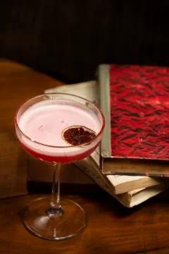 Red devil alcohol drink garnished with dried grapefruit in glass with long stem Stock Photos