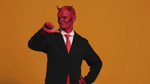 Red devil businessman showing thumbs up and down on orange background Stock Footage 294197171