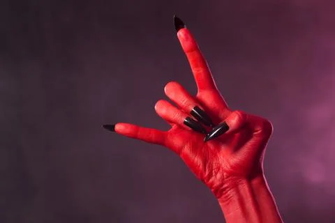 Red devil hand with black nails, heavy metal gesture Foto stock