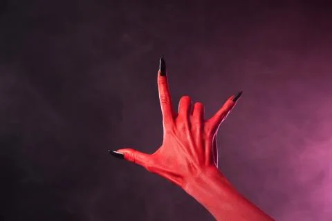 Red devil hand with black nails showing heavy metal symbol Foto stock