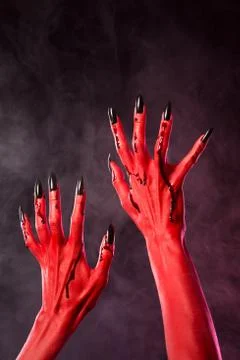 Red devil hands with black nails covered in blood Foto stock