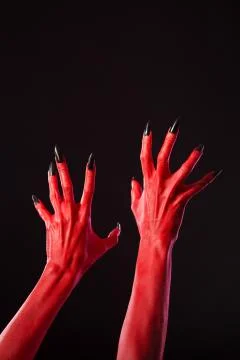 Red devil hands with sharp black nails, real body-art Stock Photos