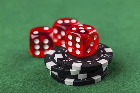 Red dice and chips on green table Photos