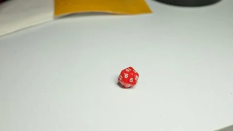 Red dice on white tabletop: d20 gaming die with numbers 6 and 19 Stock Photos