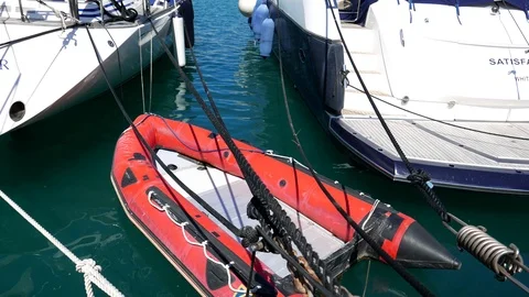 Red dinghy moving on the water between two white sailing boats Stock Footage 106664940