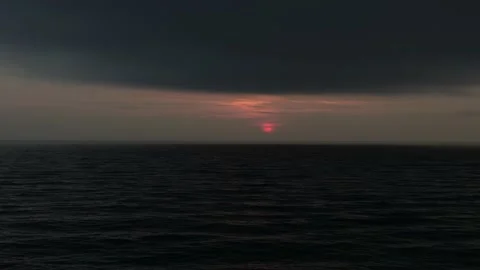 Red disc of the sun between the waves of the black sea and clouds of the black s Stock Footage 151151808