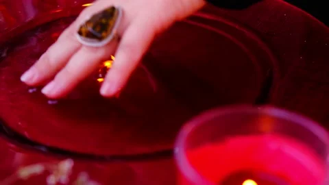 Red dish with water, reflections of lights of candles in liquid mysteriously  Stock Footage 202022247