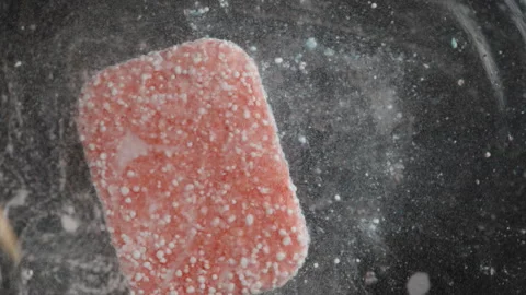 Red Dishwasher Tablet Agitated with a Stick, Rapid Dissolution Creating a Cloud Vidéo 283308109