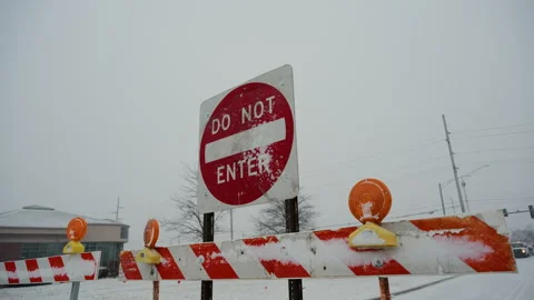 Red Do Not Enter sign stands behind road closure barriers during snowy Stock-Footage 327250956