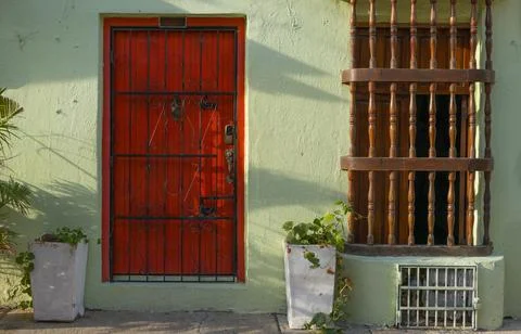 Red door with security gate on green colonial building facade Stock Photos
