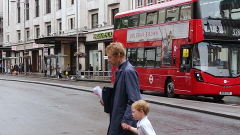 A red double decker bus passes the Kensington station / London Stock Footage 104259837