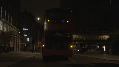 Red double-decker bus stationary on a city street at night Stock Footage 342567690