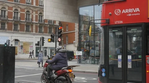 Red double decker bus waiting at traffic light and driving off at Victoria Vidéo 99996898
