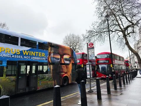 Red double decker buses and colorful advertising on a rainy London, UK stre.. Foto stock