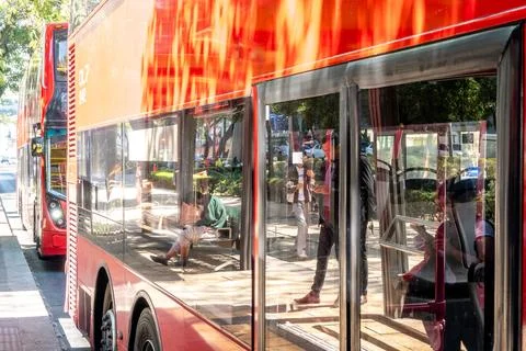 Red double decker metrobus reflecting city scene Fotos de archivo