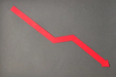 Red down arrow on grey background. Stock Photos