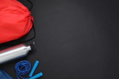 Red drawstring bag, skipping rope and thermo bottle on black background, fl.. Foto stock