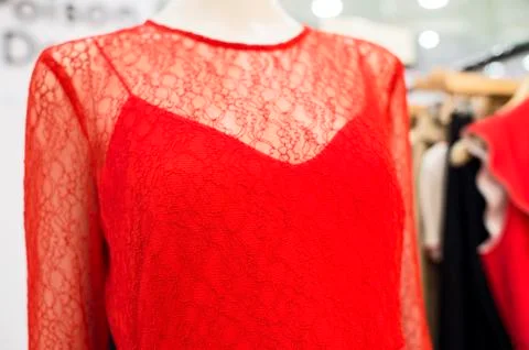 The red dress is translucent with a relief pattern on a mannequin in a shop w Stock Photos