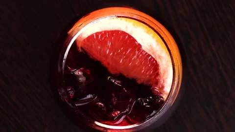 Red drink with ice and grapefruit on a wooden table Stock Footage 176389868