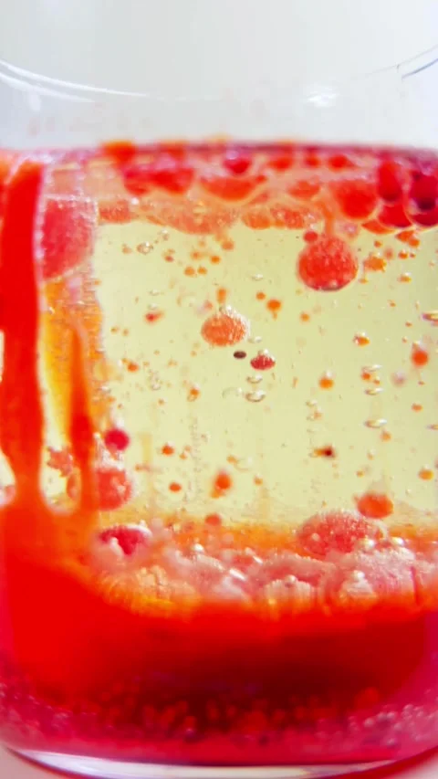 Red droplets rise and fall through yellow liquid oil Vídeos de archivo 331774701