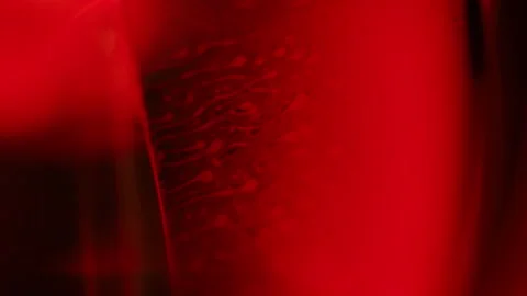 Red drops float in a thick multi-colored liquid Stock Footage 311879919