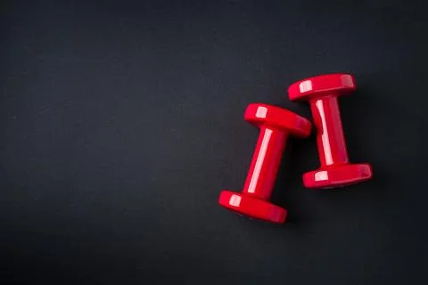 Red dumbbells on dark background symbolizing strength training, fitness and.. Stock Photos