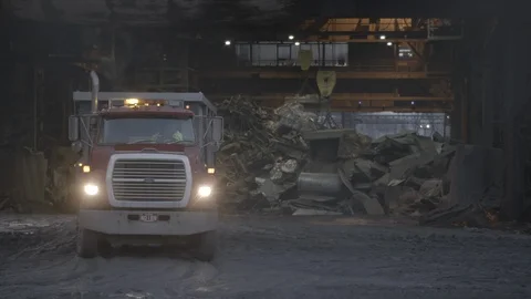 Red Dump truck backing into scrap metal warehouse Stock Footage 89945308