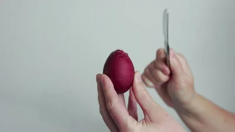 Red dyed easter egg in hands tapping with knife traditional holiday ritual Stock Footage 332679744