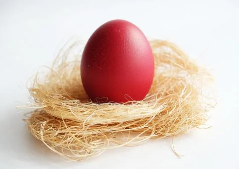 Red Easter dyed egg on coconut fiber on a white background close up Stock Photos