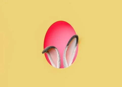 Red Easter egg and bunny ears against yellow background Stock Photos