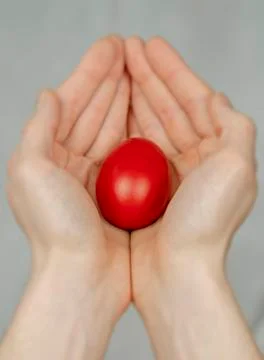 Red Easter egg lying in his palm, a religious symbol. Stock Photos