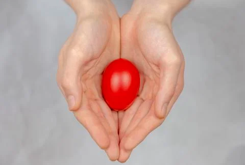 Red Easter egg lying in his palm, a religious symbol. Stock Photos