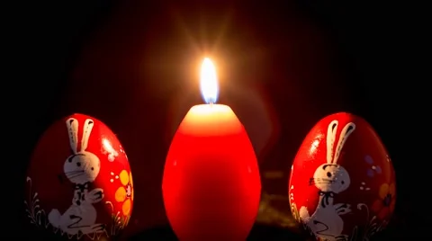 Red easter egg shape candle burning between two wooden eggs Stock Footage 48599055