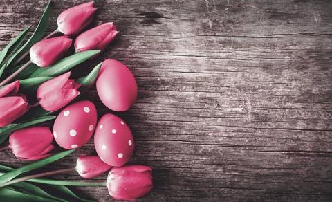 Red easter eggs and pink tulip flower on vintage wooden table from above. Foto stock