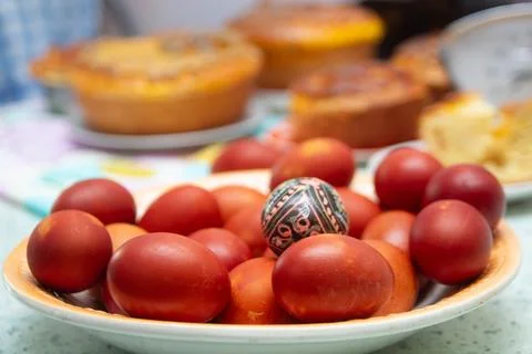 Red Easter eggs and Pysanka in a bowl with cakes background Stock Photos