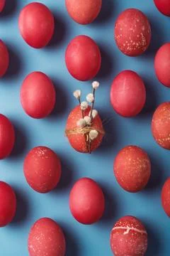 Red Easter eggs float on blue background, one egg holds pussy willow with twi Foto stock